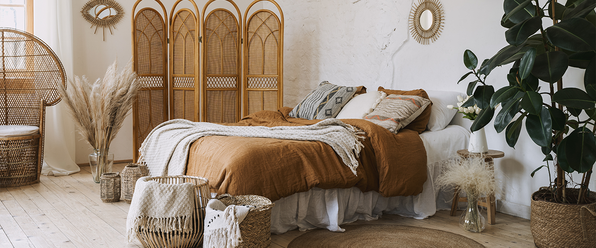 A warm, bohemian-style bedroom with natural wicker furniture and decor.