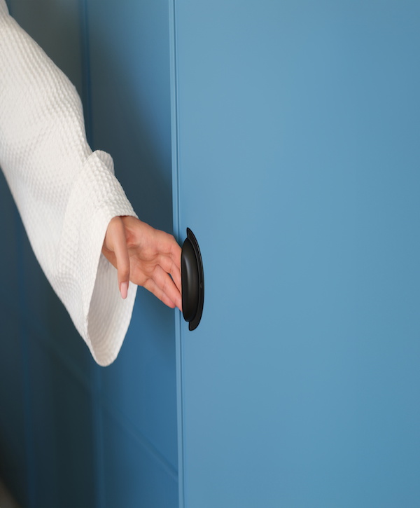 Woman hand opens blue closet door panel or modern closet door