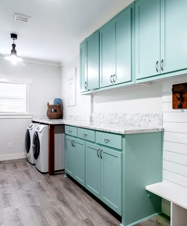 Spacious laundry room featuring teal cabinets and washer-dryer setup