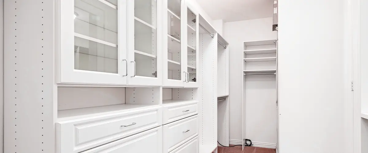 White closet system with glass-front cabinets and shelving for organized storage